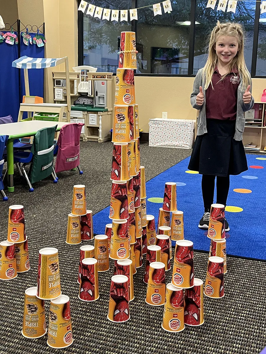 preschool-cup-stacking-stem-tower-activity Children stacking colorful cups in a tower during STEM learning activity
